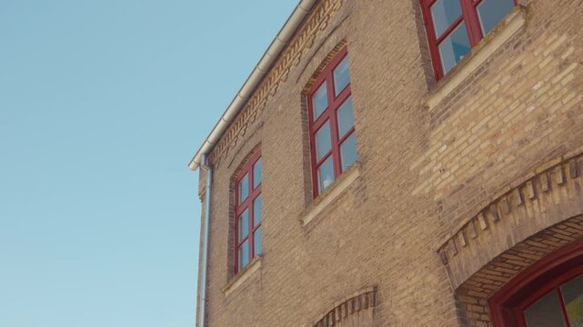 The corner of a traditional brick building stands against a clear blue sky in Haderslev, southern Denmark.