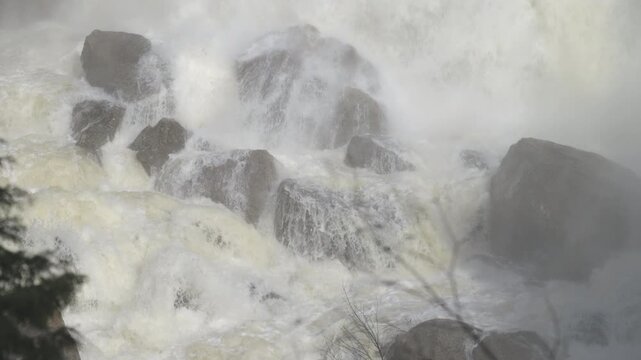 Pure white water rapids crash down steep rock formations during the peak spring melt season. Mist and spray rises from the powerful torrent at Inglis Falls in Grey County, Ontario.