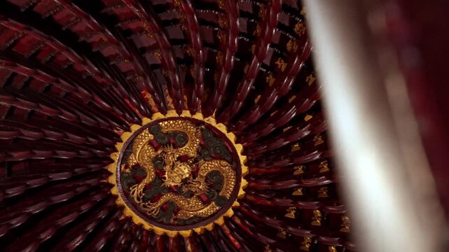 Low angle view of ornate circular ceiling design with golden dragon motif inside traditional asian temple.