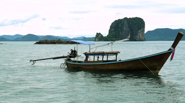 serene longtail boat floating on calm ocean water near rocky islands in nature and landscapes setting with wooden boat and blue-green hues for travel and tourism.