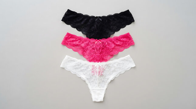 Three stacked pink and black lace women's thongs