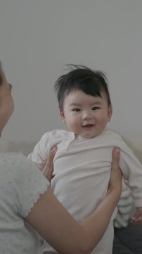 Adorable little infant toddler laughing in his mother's arms, cozy family lifestyle moments at home.