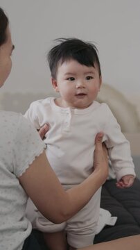 Adorable little infant toddler laughing in his mother's arms, cozy family lifestyle moments at home.