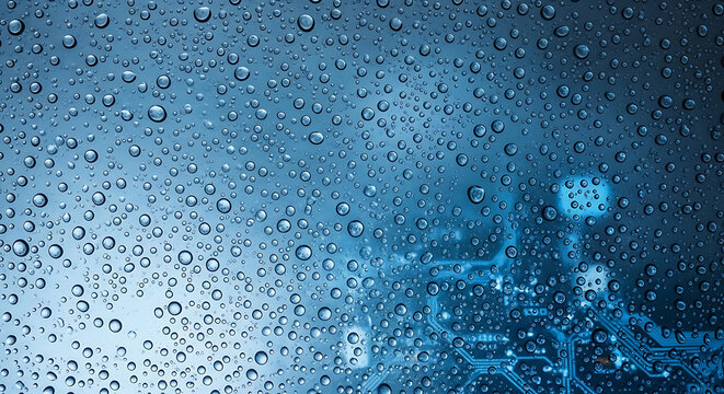 Raindrops on a dark blue digital screen with icons - Close-up shot of raindrops falling on a dark blue digital screen displaying colorful app icons in a modern tech setting.