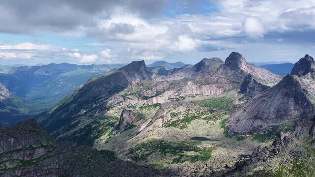 High angle drone shot of majestic mountain ridges and alpine lake hidden in deep coniferous woodland during sunny summer season.