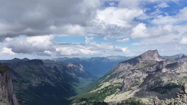 High angle drone shot of majestic mountain ridges and alpine lake hidden in deep coniferous woodland during sunny summer season.