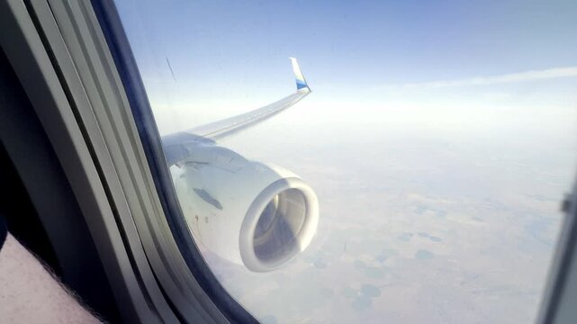 Airplane wing and jet engine seen from a passenger window while flying over Washington state.