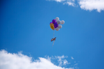 Fototapeta premium Bunch of Balloons With a Love Sign Flying in a Blue Sky