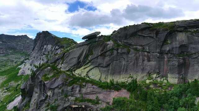 High angle drone shot of majestic mountain ridges and alpine lake hidden in deep coniferous woodland during sunny summer season.
