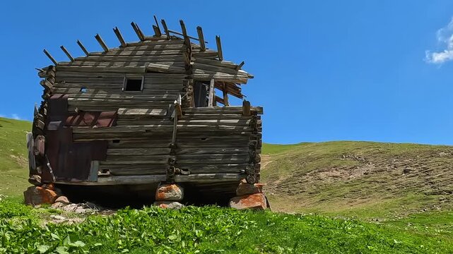Ruined houses passing in wide shot beside rural road to Green Lake, showing abandoned wooden buildings in Georgian highlands for travel footage, village history, mountain tourism, and regional