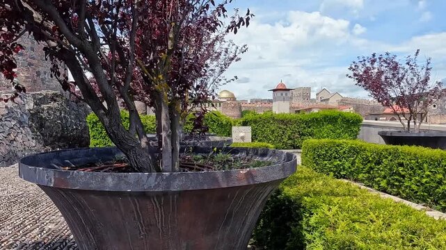 Rabat fortress panning wide shot across stone courtyard, garden trees, water basin, and hill landscape in Georgia for heritage tourism, Caucasus travel, medieval architecture, and historical