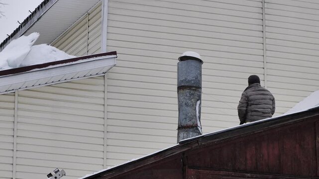 Man performing chimney maintenance on a snowy roof during cold winter weather