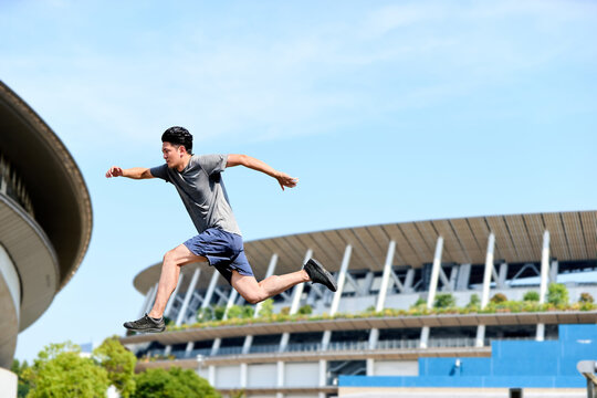 前方へ全力で大きくジャンプし推進力や躍進やチャレンジ精神を表現する20代のスポーティーな日本人の男性