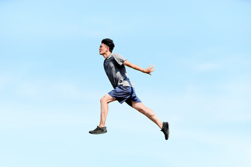 Obraz premium 青空を背景に空中でダイナミックにジャンプする躍動感あふれる20代から30代の男性の横向きの全身写真