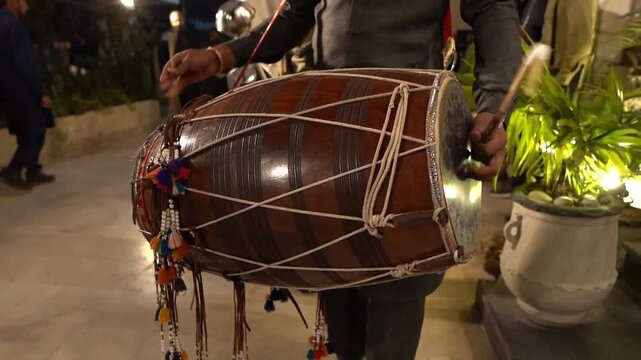 Cinematic slow-motion footage of a traditional dhol player performing at a Pakistani wedding celebration. Close-up view of rhythmic drumming, cultural music, festive atmosphere, and live entertainment