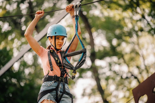 Woman ziplining in adventure park wearing safety equipment