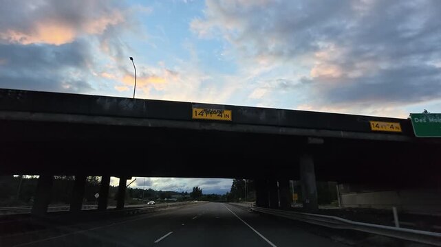 Driving on highway under overpass at twilight in Washington