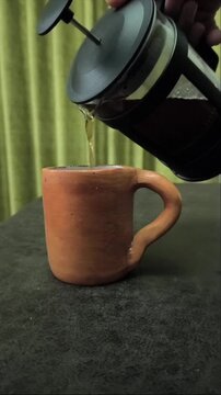Serving coffee from a French press into a ceramic cup