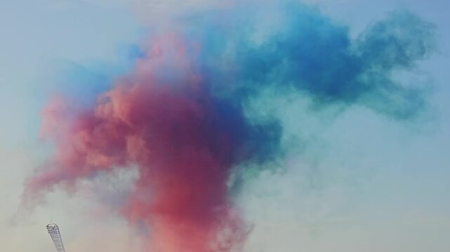 Colorful smoke fills the sky during a celebration at sunset in a city park