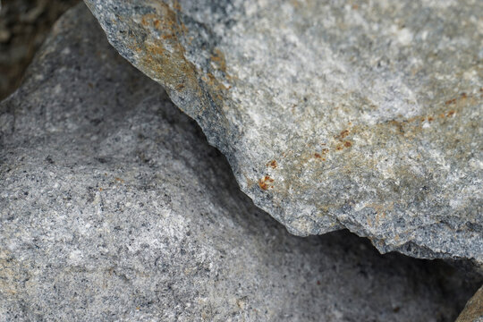 A detailed close-up shot of a rough and rugged gray granite rock surface showcasing natural mineral veins, fine grains, and organic geological patterns.                     