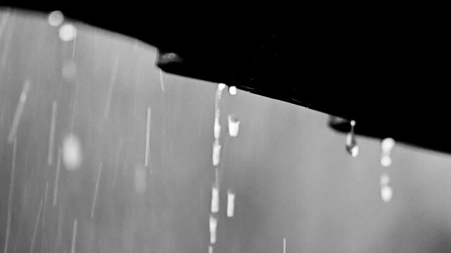 Rain dripping from a dark overhang. The heavy rain creates a misty atmosphere, hinting at a stormy weather