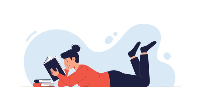 Relaxed young woman lying on her stomach while reading a book with a pile of books on a clean background.