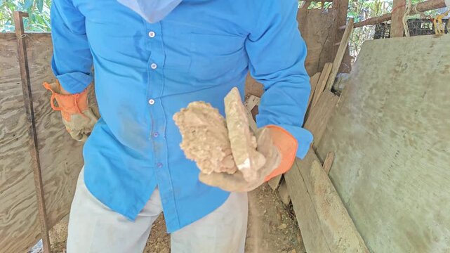 Person collecting small rocks from ground cleared with pickaxe tool