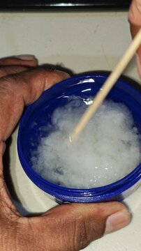 Spoon stirring partially crystallized solid white coconut oil product