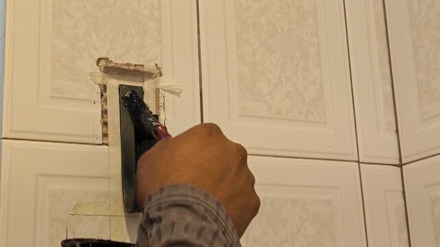 Applying protective black paint with brush on steel flat bar base
