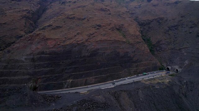 Vehicles travel beside steep rocky slopes toward Zulam Kot Tunnel on the Swat Kalam Motorway, Khyber Pakhtunkhwa, Pakistan