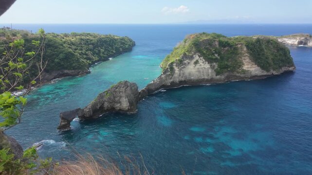 Natural rock formation near Diamond Beach / Pantai Diamond in Nusa Penida, Bali. One of a thousand islands. A slow motion push in shot of dramatic cliffs and crystal-clear turquoise waters.
