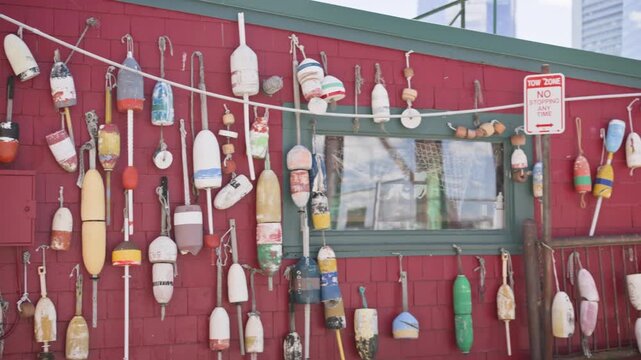 Cinematic pan right across colorful fishing buoys mounted on a weathered wall in Boston, Massachusetts. Nautical decorations and maritime character create an authentic New England co