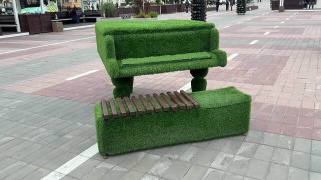 A unique piano and bench sculpture made of artificial grass stands in a city square in Ulan-Ude, Russia