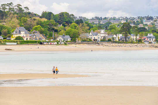 People walking on a sand beach by the waters edge in low tide