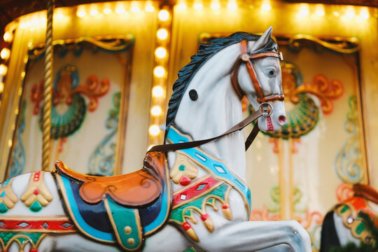 Classic white carousel horse with colorful saddle standing on a bright vibrant merry go round
