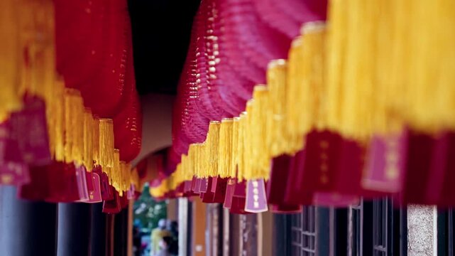 Red lanterns with gold tassels hanging in row at buddhist temple.