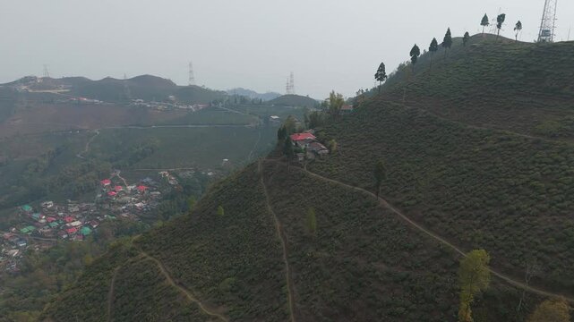 A stunning 4K drone view of a peaceful village near Mirik, Darjeeling, featuring lush farmland, green landscapes, and a winding zigzag village road surrounded by scenic Himalayan beauty.	