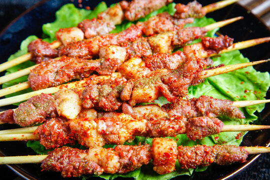 Zibo Style Barbecue Meat Skewers at Night Market with Charcoal Flames and Fresh Garnish