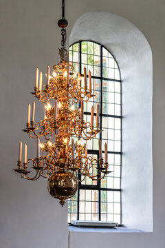 Ornate brass chandelier with candles hanging inside a historic church