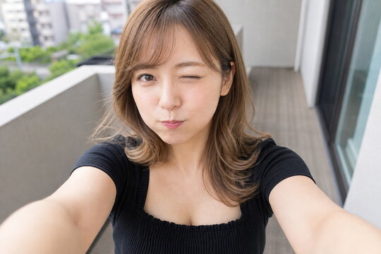 マンションのベランダでウインク黒いトップスの女性自撮り