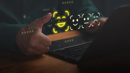 Hand showing thumbs up with laptop and glowing emoji rating hologram. Positive customer review, excellent service satisfaction and digital feedback concept. © ParinPIX