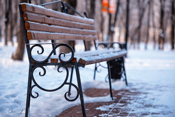 Naklejka premium park bench on a winter alley at snowfall. bench with snow after snowstorm or in snow calamity in europe