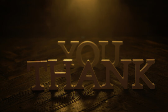 Thank You Text in Wooden Letters with Dramatic Lighting on Dark Wood Background