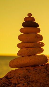 Stones balance sunset A stack of rocks on a beach at golden hour symbolizing peace and tranquility.