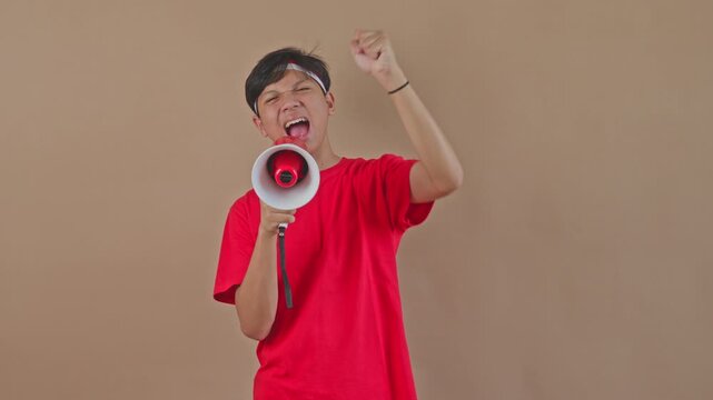Passionate Asian boy yelling through loudspeaker while celebrating victory for Independence Day in studio