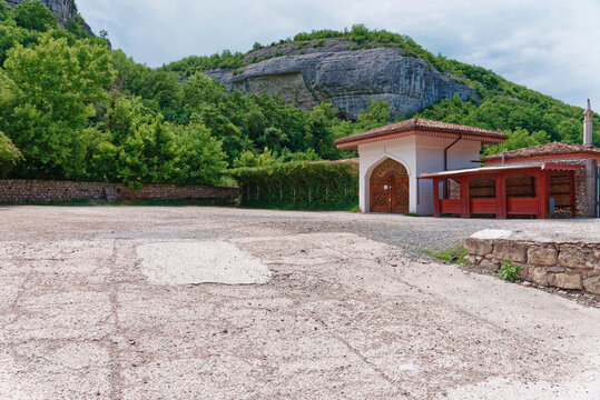 Traditional tatar arched gate building with wooden doors against limestone cliffs in Bakhchisarai