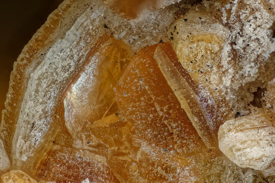 Macro photography of polychrome orange Quintinite crystals texture. Mineral specimen background with zoned crystalline structure from Kovdor