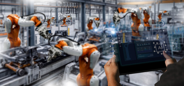 Hands use a tablet to monitor robotic arms on an automated factory line, tracking production data through a digital dashboard for manufacturing control and industrial operations management.
