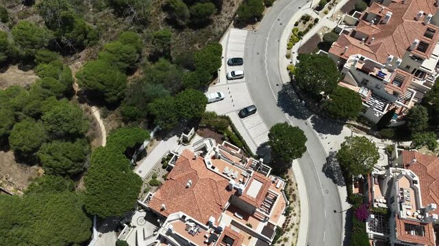 Aerial overview of Quinta do Lago resort buildings in Vale de Lobo, Algarve, Portugal, Europe. Shot of rooftops of luxury cottages in green landscape with mountains on background. Golf fields.