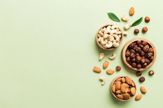 Assortment of nuts in wooden bowl on colored table. Cashew, hazelnuts, walnuts, almonds. Mix of nuts Top view with copy space